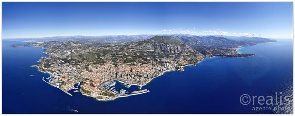 Vue panoramique aérienne de Monaco, prise à haute altitude. Le temps très clair permet de voir les alpes et les côtes azuréennes et italiennes.