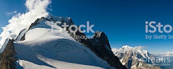 Whisps of cloud swirling round the dramatic summit of Aiguille Verte and the rocky pinnacles of les Drus overlooking the deep blue high altitude skies, the green slopes of the Reserve Naturelle des Aiguilles Rouges and the snow capped domes of Mont Blanc, Europe's highest mountain. ProPhoto RGB profile for maximum color fidelity and gamut.