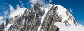 Huge walls of rock, jagged spires and steep snow slopes in this awe inspiring Alpine panoramic vista of the Mont Blanc massif against a deep blue wilderness sky and white whisps of high altitude clouds. ProPhoto RGB profile for maximum color fidelity and gamut.