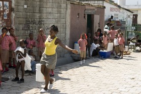 avec médecins sans frontières dans cité soleil - femme transportant de l'eau dans les rues de cité-soleil sous le regard des ecoliers, dans une des rares rues pavees du bidonville
