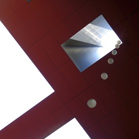 Eine Kette mit Kugeln hängt aus einem Lichtschacht eines hohen Gebäudes hinab 