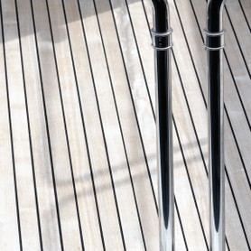 Zwei edle Stangen aus Chrom werfen einen Schatten auf den edlen Holzboden einer edlen Yacht