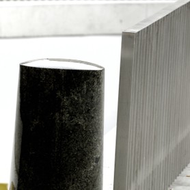 Ein schwarzer Pfeiler an einem grauen Zaun schafft eine grafische, abstrakte Wirkung 