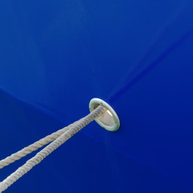 Die Befestigungstaue eines Bootes verlaufen durch eine Öffnung in einer blauen Schiffswand und spiegeln sich an ihr