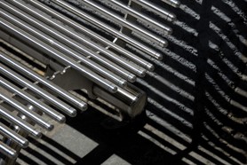 Der Schatten einer Sitzbank mit Metallstäben wird an einer Wand abgebildet und erzeugt ein Muster von parallelen Geraden