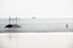 India Follows Raabe 01 - Mit dem Sonnenaufgang nähern sich die Pilger dem nebel- und rauchverhangenen Ganges in Indien, um ihn zu überqueren und in der heiligen Stadt Varanasi die Toten zu verbrennen