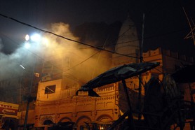 India Follows Raabe 18 - Ám frühen Morgen in Varanasi. Der Rauch der verbrannten Toten steht über der Stadt. Die Angehörigen übernachten unter den Strohdächern.