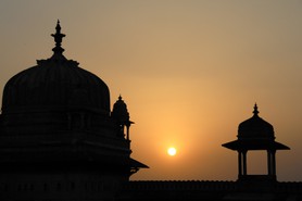 India Follows Raabe 33 - Sonnenuntergang hinter einem Tempel in Indien.  Tausendundeine Nacht: Die untergehende Sonne mit ihrem rötlichen Licht verzaubert die Türme eines indischen Palastes.