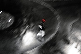 Whirl of time - Ein Mensch mit rotem Helm eilt auf regennasser Straße durch die Nacht - getrieben durch die Zeit.