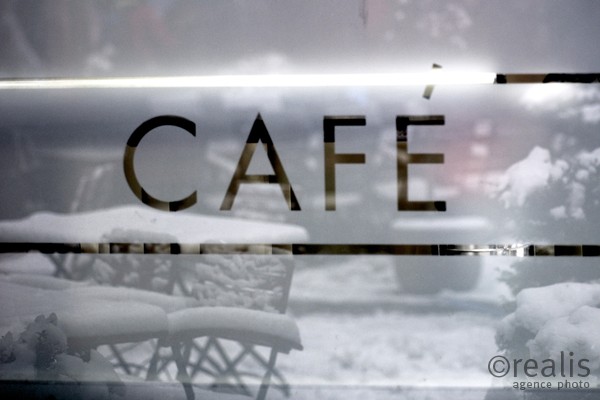 Winter-Café - In der Fensterscheibe eines Cafés mit der Aufschrift " Café " spiegelt sich die Winterlandschaft auf den Stühlen und Tischen des Außenbereichs des Cafés